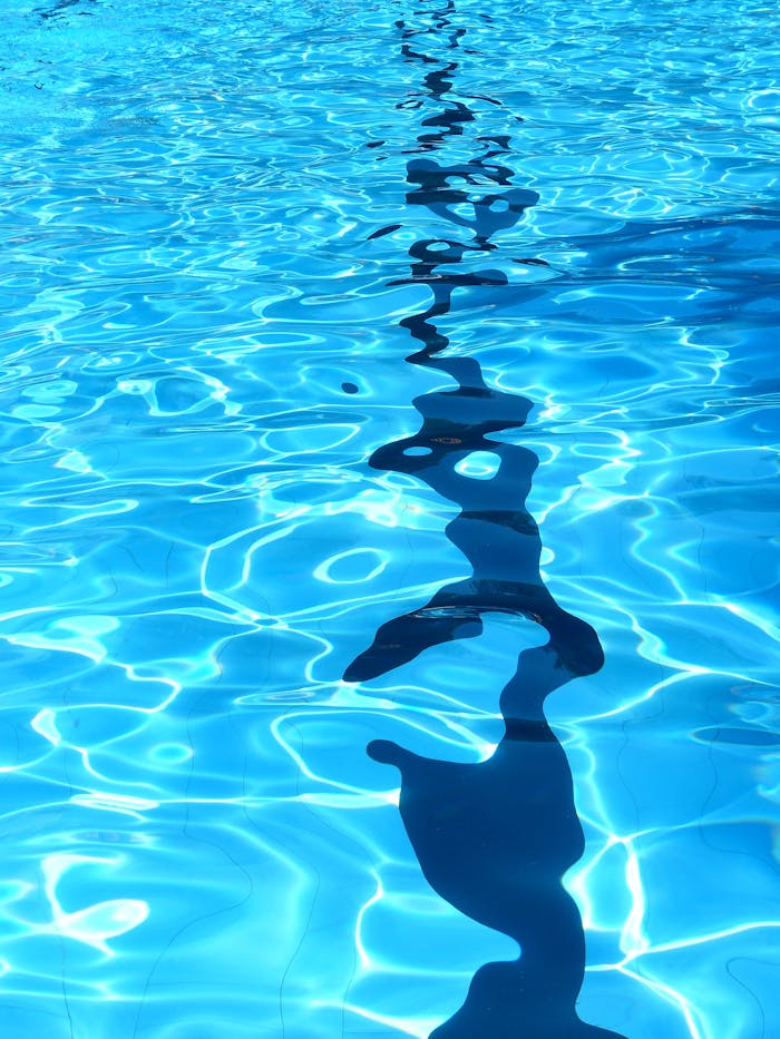 Close-up of a swimming pool with sunlight creating ripples and reflections on the water surface.